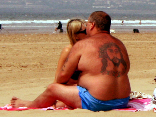 Holy back tattoo: Jesus faces other way while couple makes out on beach 