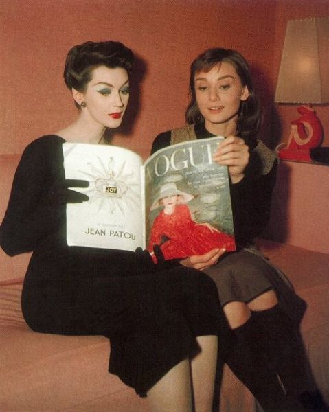 Model Dovima and Audrey Hepburn peruse Vogue magazine C 1950s